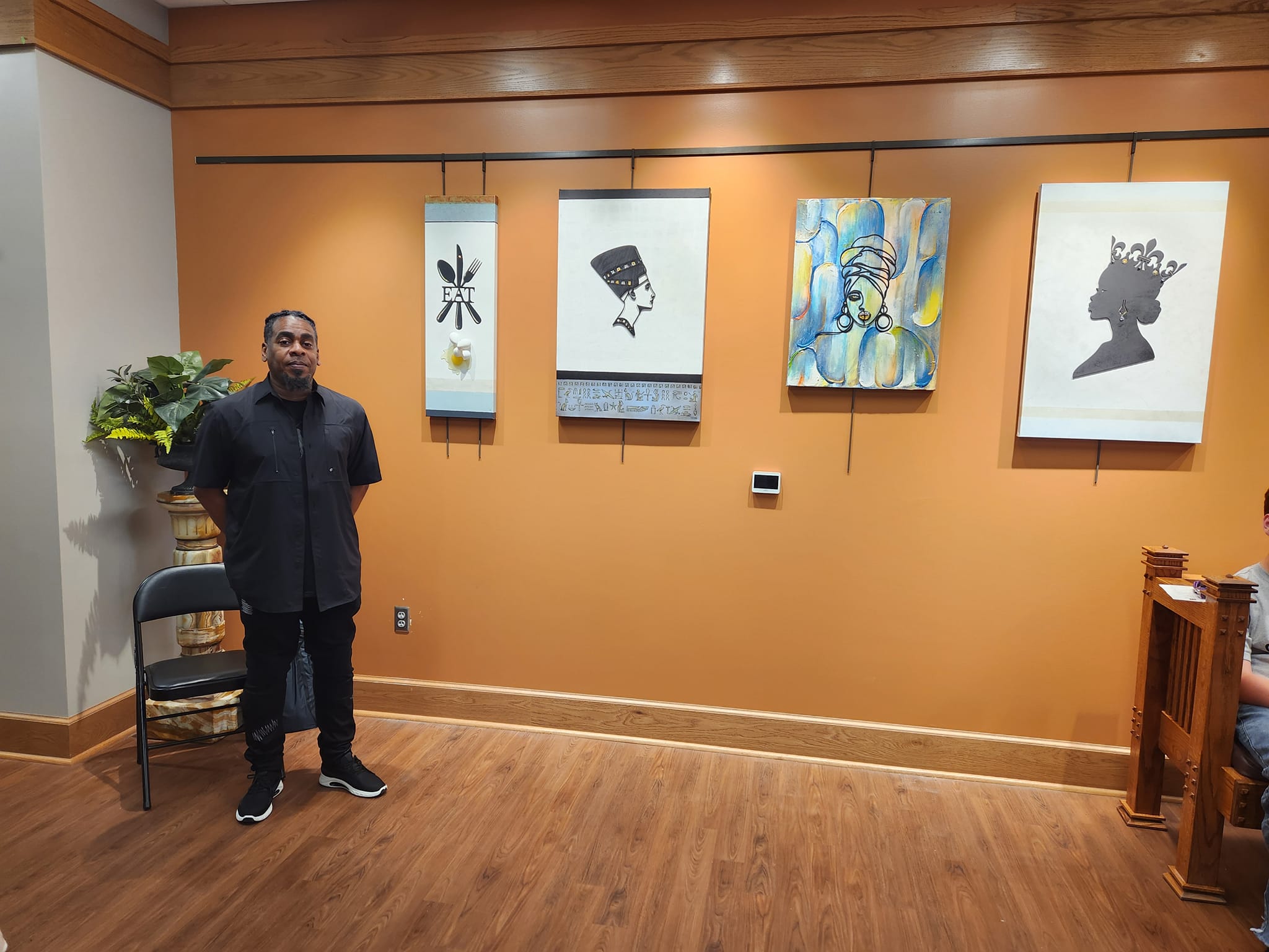 man standing by a wall filled with artwork